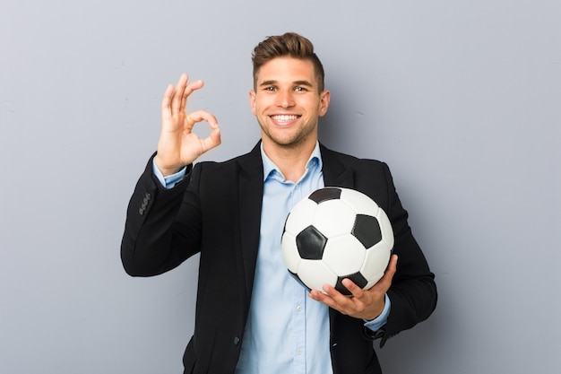 Young soccer trainer cheerful and confident showing ok gesture.