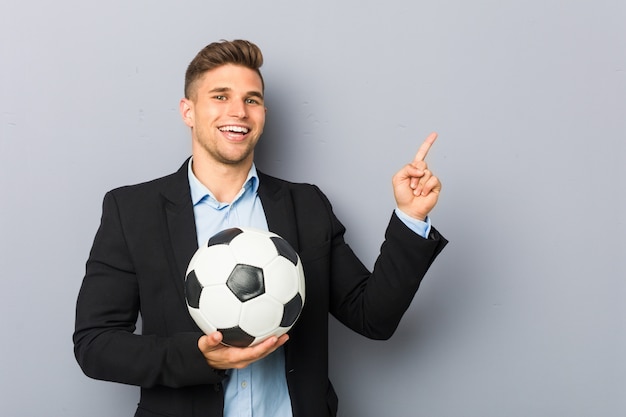 Young soccer trainer smiling cheerfully pointing with forefinger away.