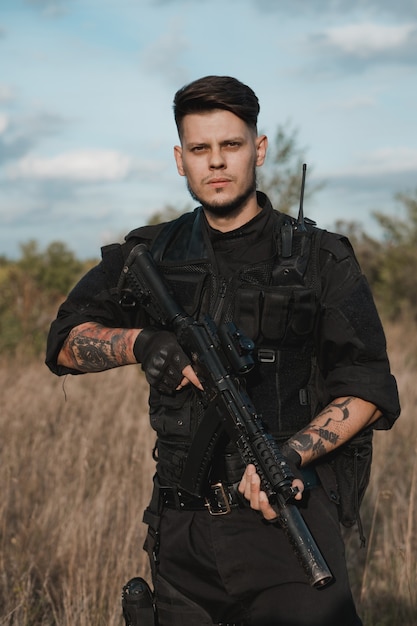 Young soldier in black uniform with an assault rifle