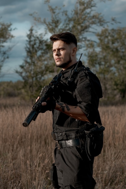 Young soldier in black uniform with an assault rifle