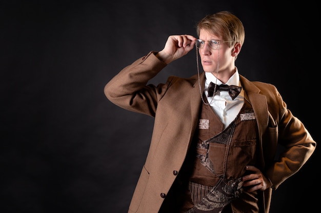 A young, solid man in the image of a Victorian scientist, a university teacher or a natural scientist. Vintage retro suit, young attractive man in a vest and bow tie