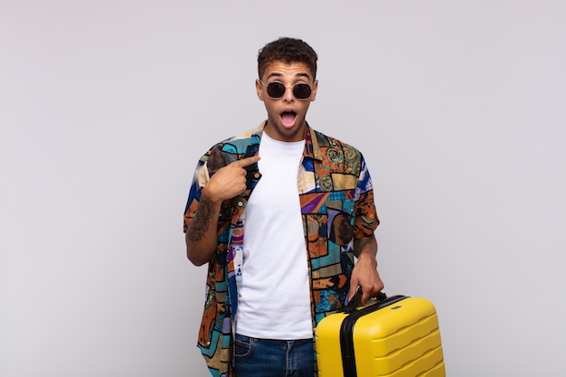 Young south american man looking shocked and surprised with mouth wide open, pointing to self