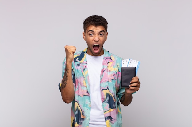 Young south american man shouting aggressively with an angry expression or with fists clenched celebrating success