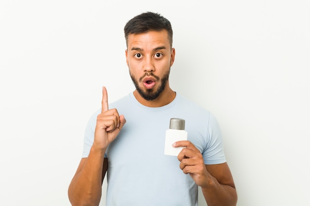 Young south-asian man holding an after shave cream having some great idea, concept of creativity.