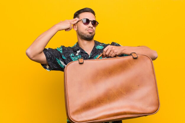 Young south-asian man holding a leather case.