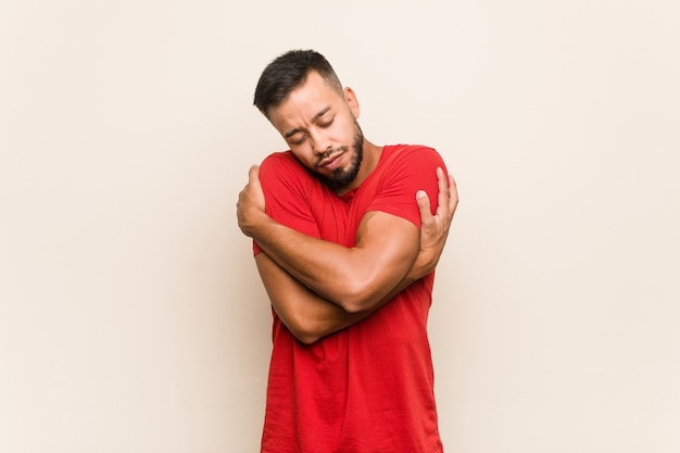 Young south-asian man hugs, smiling carefree and happy.