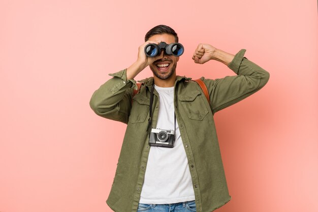 Young south-asian man looking through a binoculars.