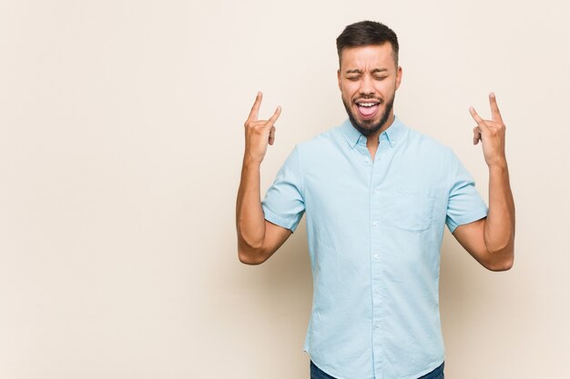 Young south-asian man showing rock gesture with fingers