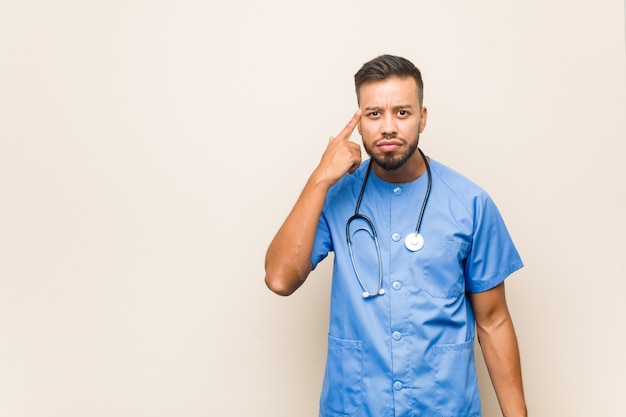 Young south-asian nurse man showing a disappointment gesture with forefinger.