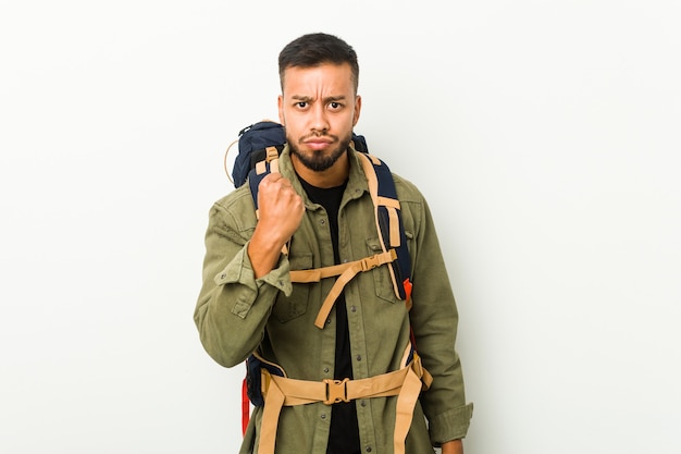 Young south-asian traveller showing fist, aggressive facial expression.