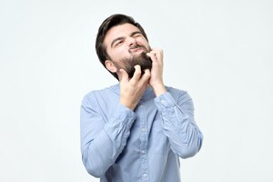 Young spanish man with black beard scratching his face