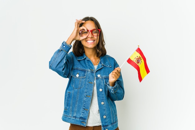 Young spanish woman holding a flag isolated