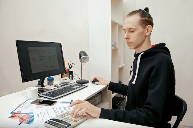 A young specialist works with financial documents at a computer