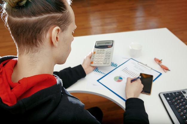 A young specialist works with financial documents at a computer