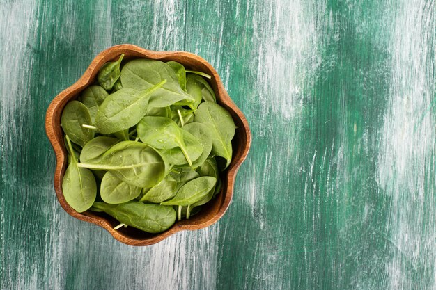 Young spinach leaves in a wooden bowl on wooden background