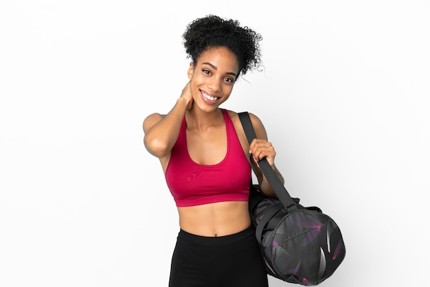 Молодая спортивная афро-американская женщина со спортивной сумкой на синем фоне смеется