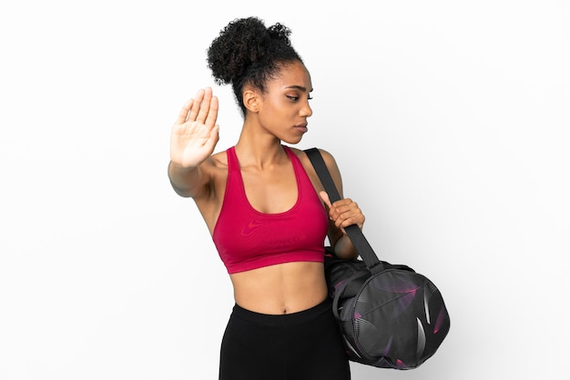 Young sport african american woman with sport bag isolated on blue background making stop gesture and disappointed