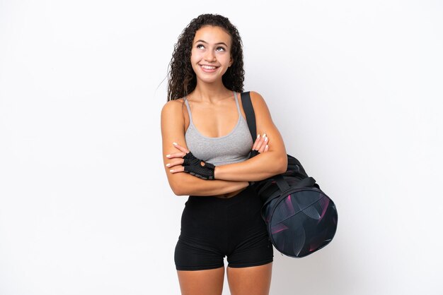 Photo young sport arab woman with sport bag isolated on white background looking up while smiling