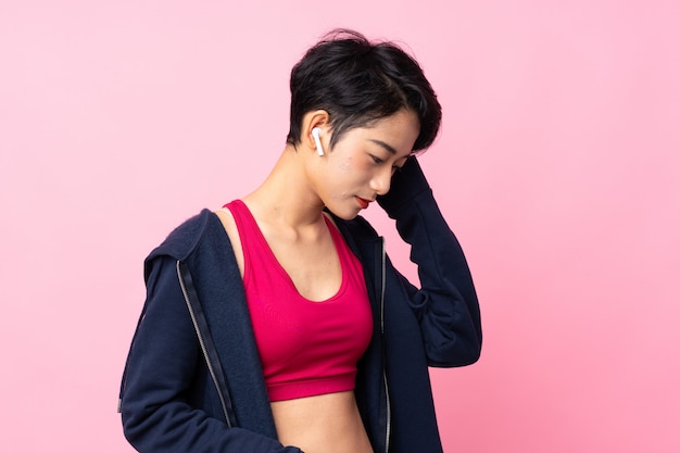 Photo young sport asian woman over isolated pink wall listening music