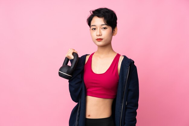 격리 된 분홍색 벽 kettlebell와 역도를 만들고 전면을 찾고 젊은 스포츠 아시아 여자