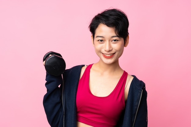 Young sport Asian woman over isolated pink wall making weightlifting