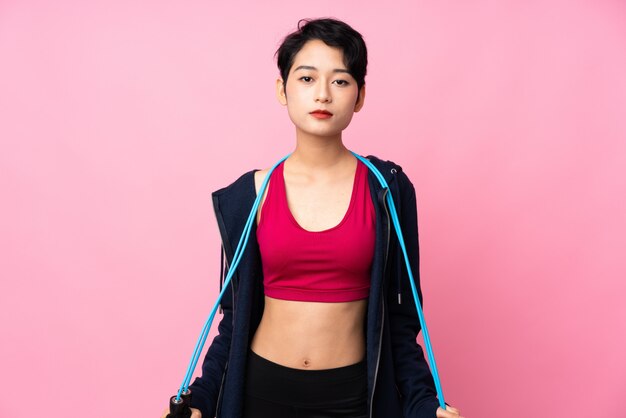 Young sport Asian woman over isolated pink wall with jumping rope