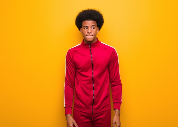 Young sport black man over an orange wall thinking about an idea