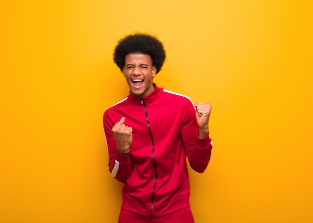 Young sport black man over an orange wall who does not surrender