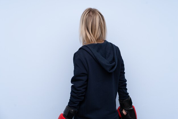 Young sport blonde woman over isolated blue wall with boxing gloves