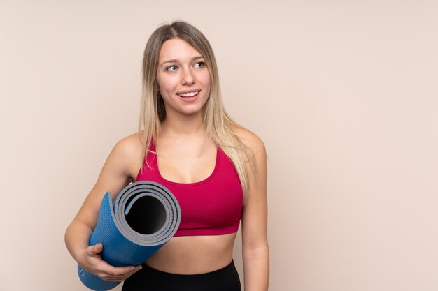 Donna bionda di giovane sport con una stuoia e sorridere