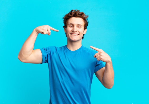 Young sport boy smiling confidently pointing to own broad smile, positive, relaxed, satisfied attitude