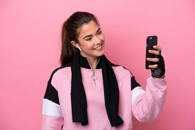 Young sport brazilian woman isolated on pink background making a selfie