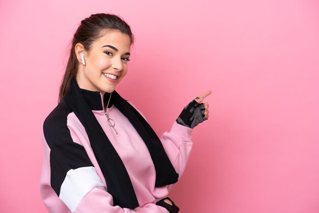 Young sport Brazilian woman isolated on pink background pointing finger to the side