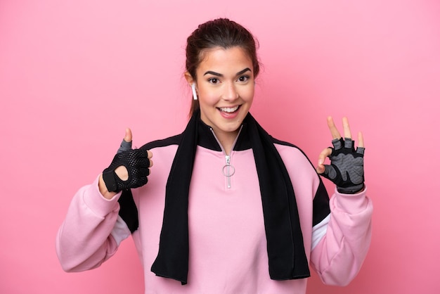 Young sport Brazilian woman isolated on pink background showing ok sign and thumb up gesture