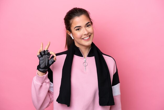 Young sport Brazilian woman isolated on pink background showing ok sign with fingers