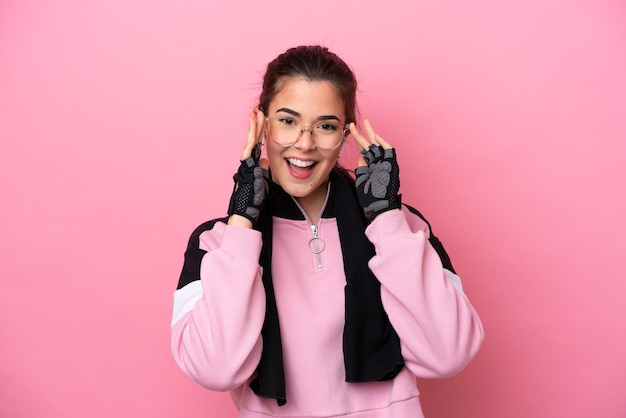 Young sport Brazilian woman isolated on pink background with glasses and surprised