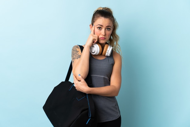 Young sport Brazilian woman with sport bag isolated on blue thinking an idea