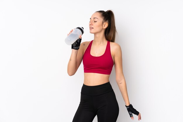 Young sport brunette woman over isolated white wall with sports water bottle