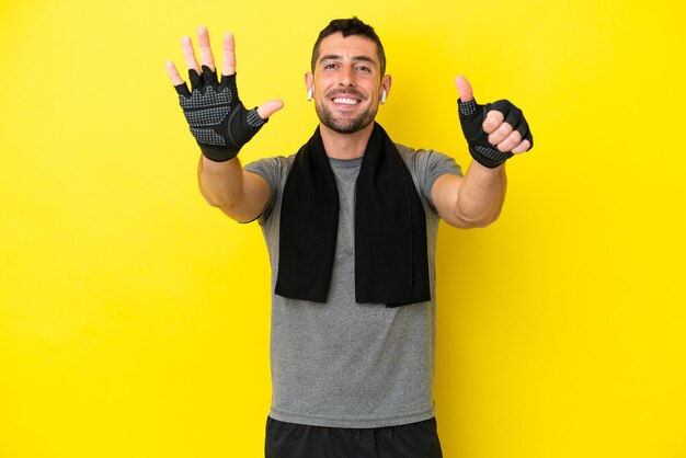 Young sport caucasian man isolated on yellow background counting six with fingers