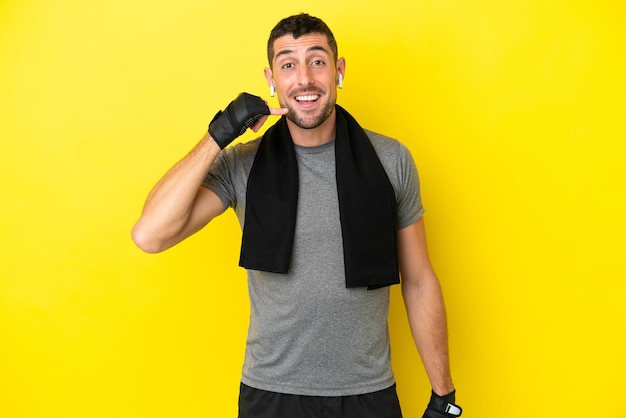 Young sport caucasian man isolated on yellow background making phone gesture. Call me back sign