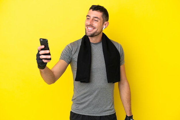 Young sport caucasian man isolated on yellow background making a selfie