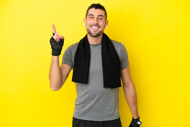 Young sport caucasian man isolated on yellow background showing and lifting a finger in sign of the best