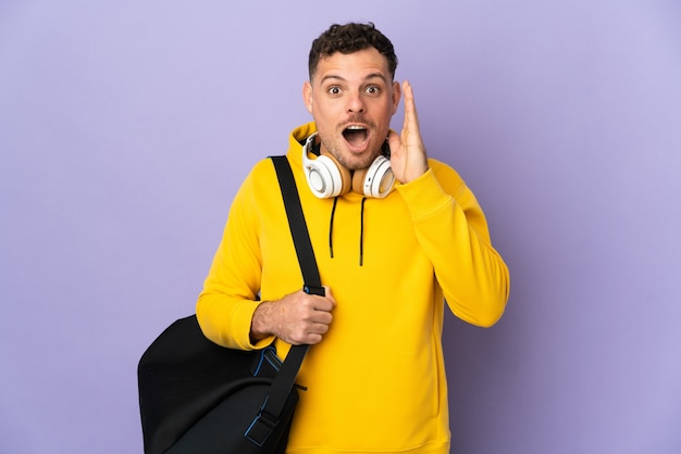 Young sport caucasian man with bag isolated purple with surprise and shocked facial expression