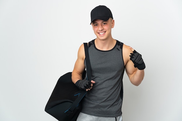 Young sport caucasian man with bag isolated on white giving a thumbs up gesture