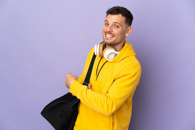 Young sport caucasian man with bag pointing back