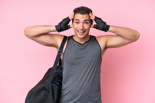 Молодой спортивный кавказец со спортивной сумкой на розовом фоне с удивленным выражением лица