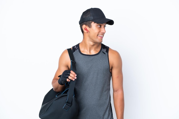 Young sport caucasian man with sport bag isolated on white background looking side