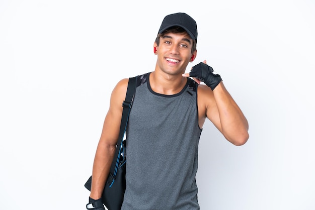 Young sport caucasian man with sport bag isolated on white background making phone gesture. Call me back sign