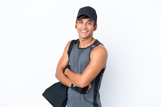 Young sport caucasian man with sport bag isolated on white background with arms crossed and looking forward