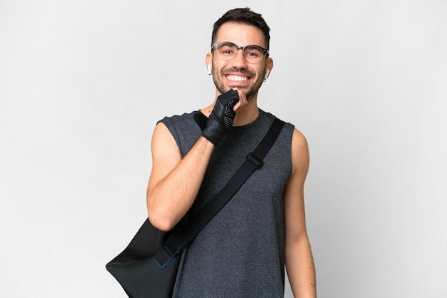 Young sport caucasian man with sport bag over over isolated white background with glasses and smiling